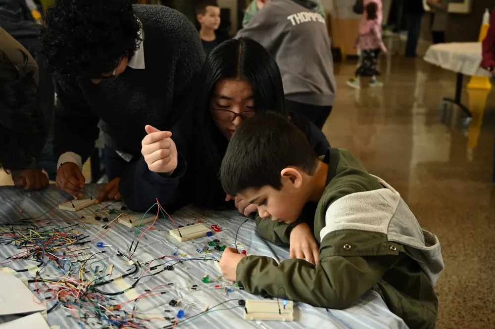 A student leader and kids building circuits together