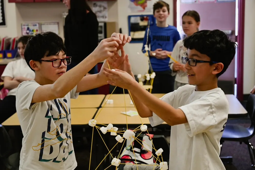 Two students building a tower out of spaghetti and marshmallows